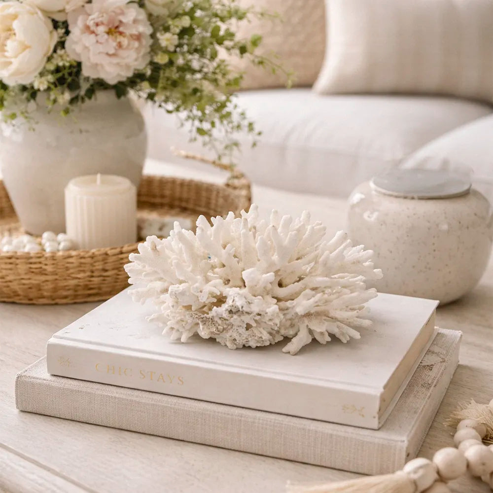 Decorative setting with vintage elkhorn coral, books, and flowers on a light surface.