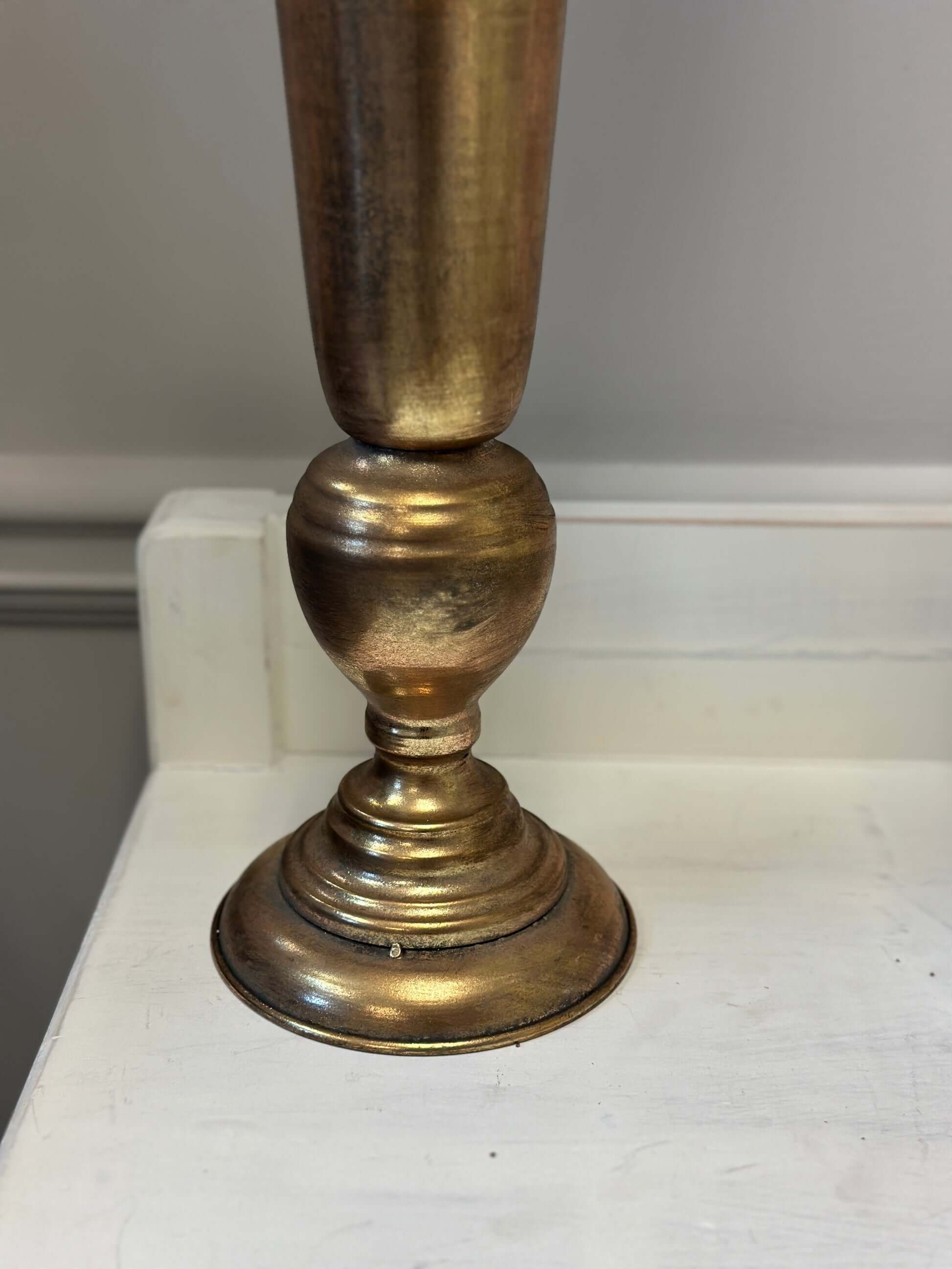 Brass candlestick on a white surface with a neutral background