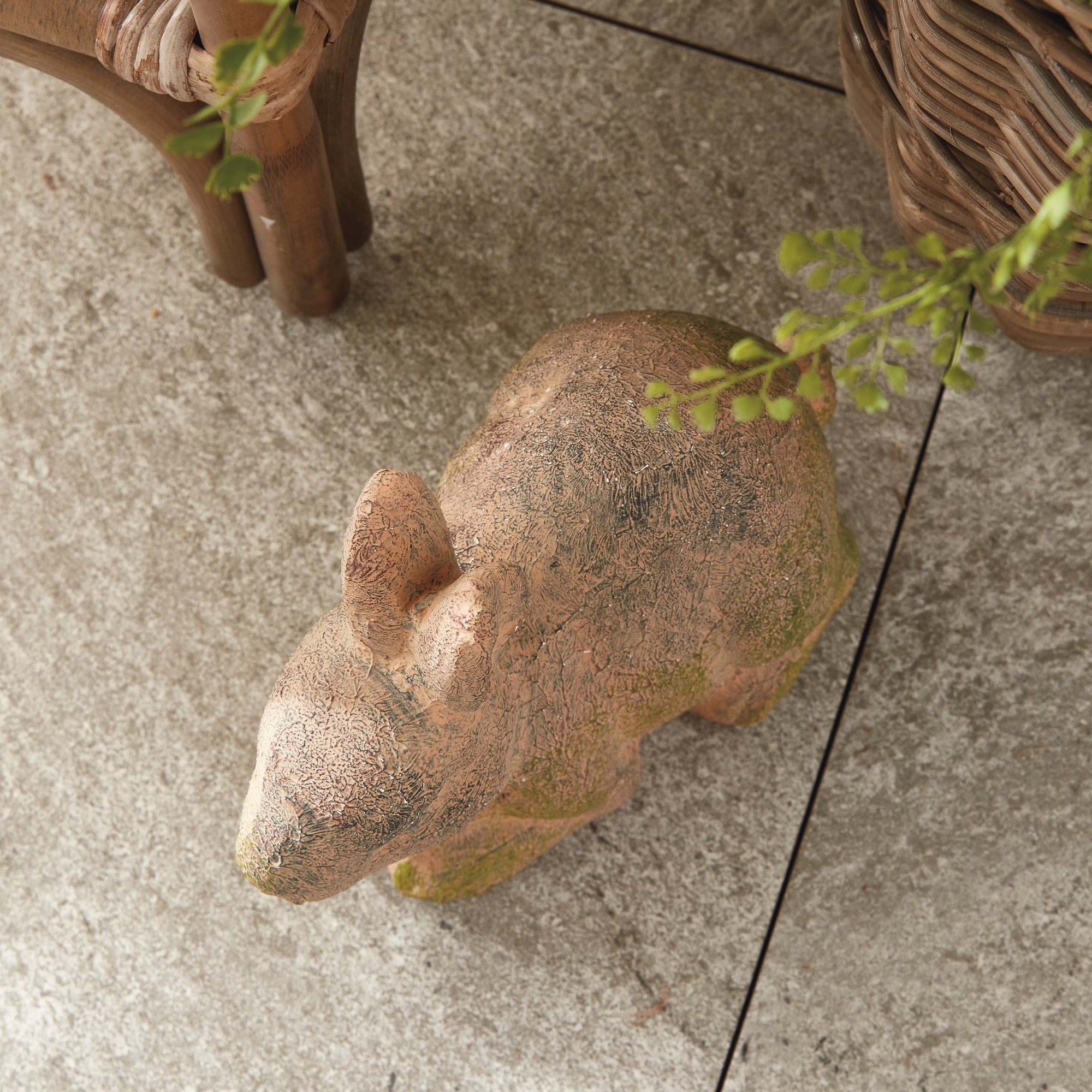 Stone bear sculpture on a concrete surface with plants around