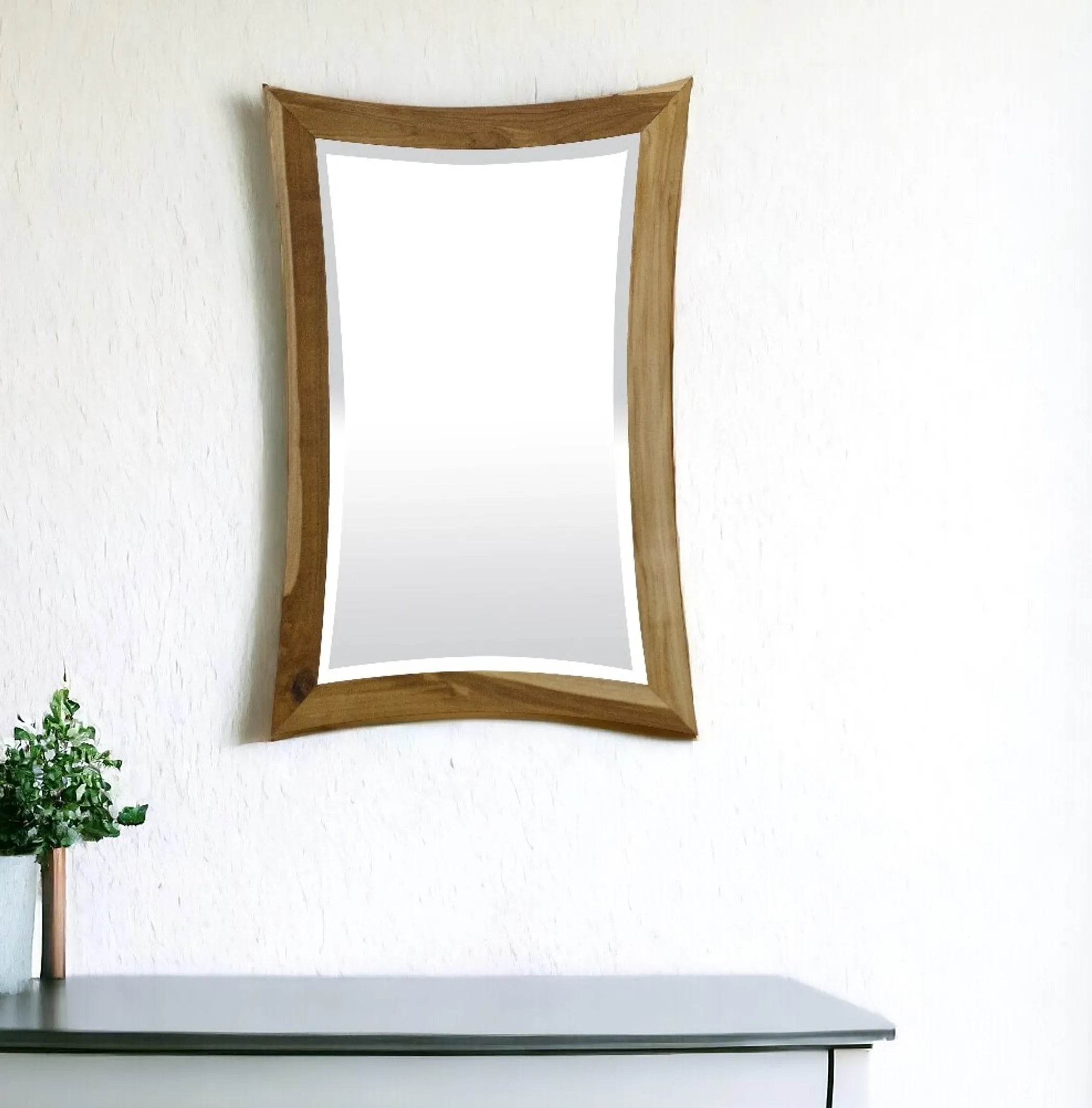 Wooden-framed mirror on a white wall with a plant in the foreground