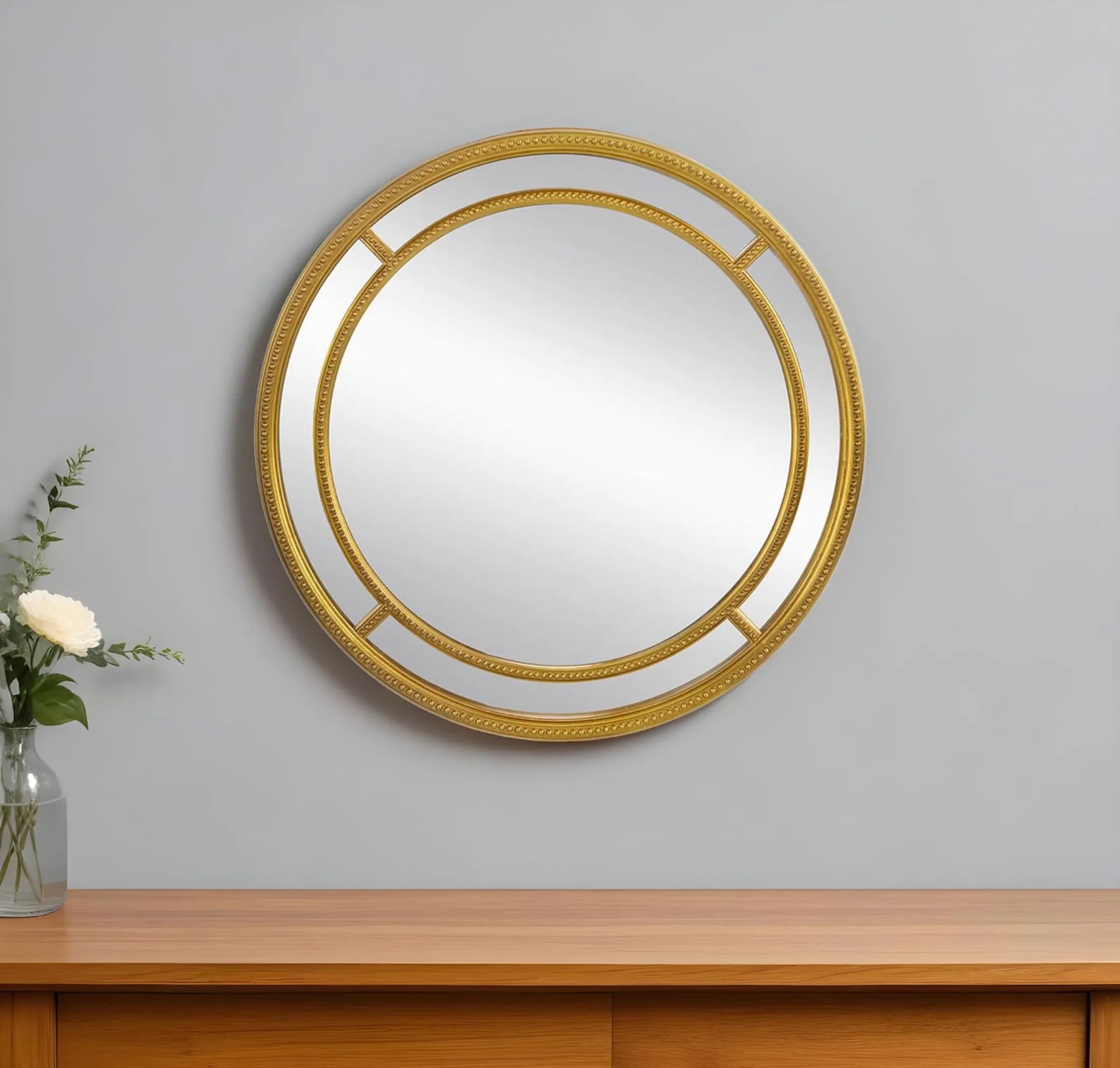 Round gold-framed mirror on a gray wall with a wooden console table below.