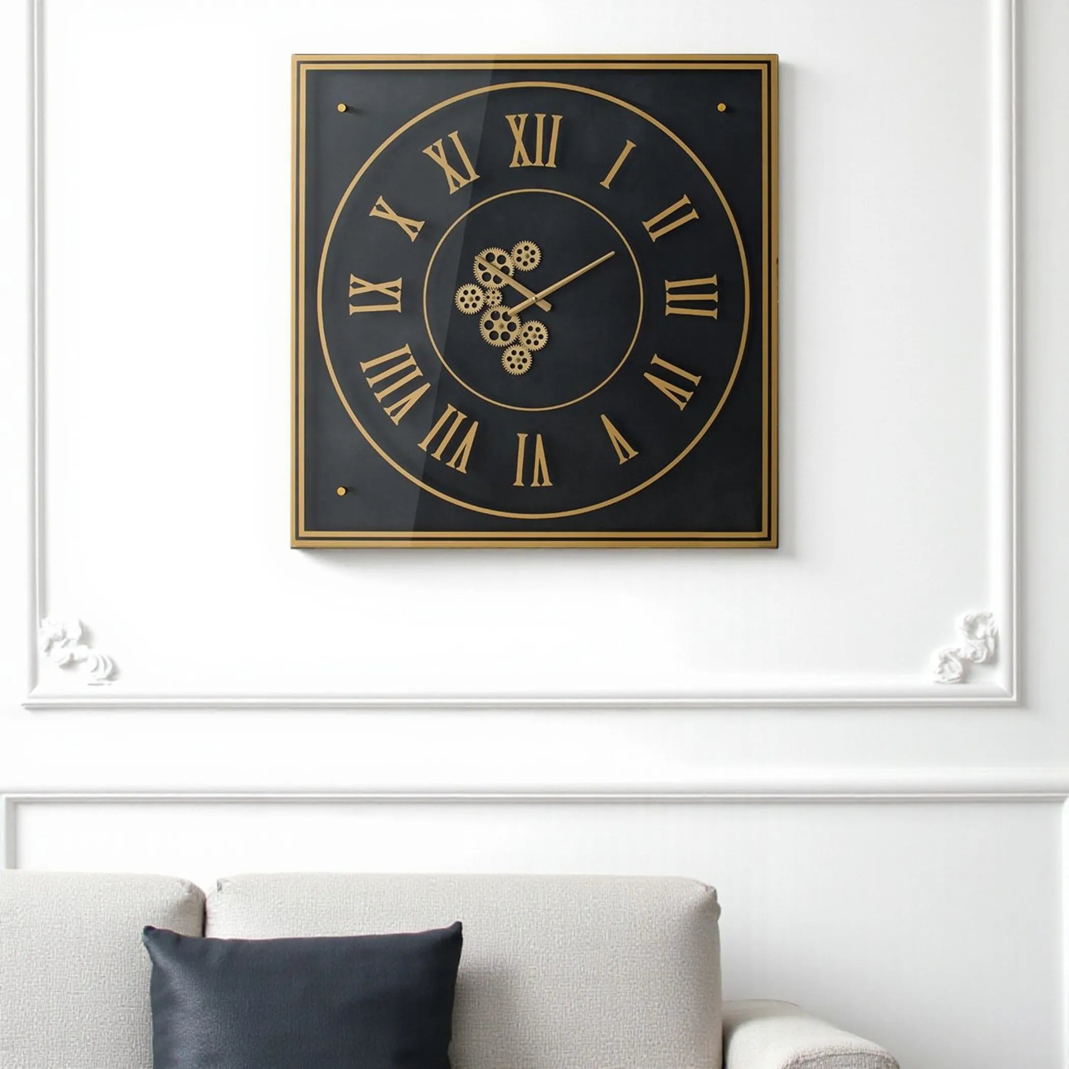 Decorative wall clock with gold Roman numerals on a white wall above a sofa.