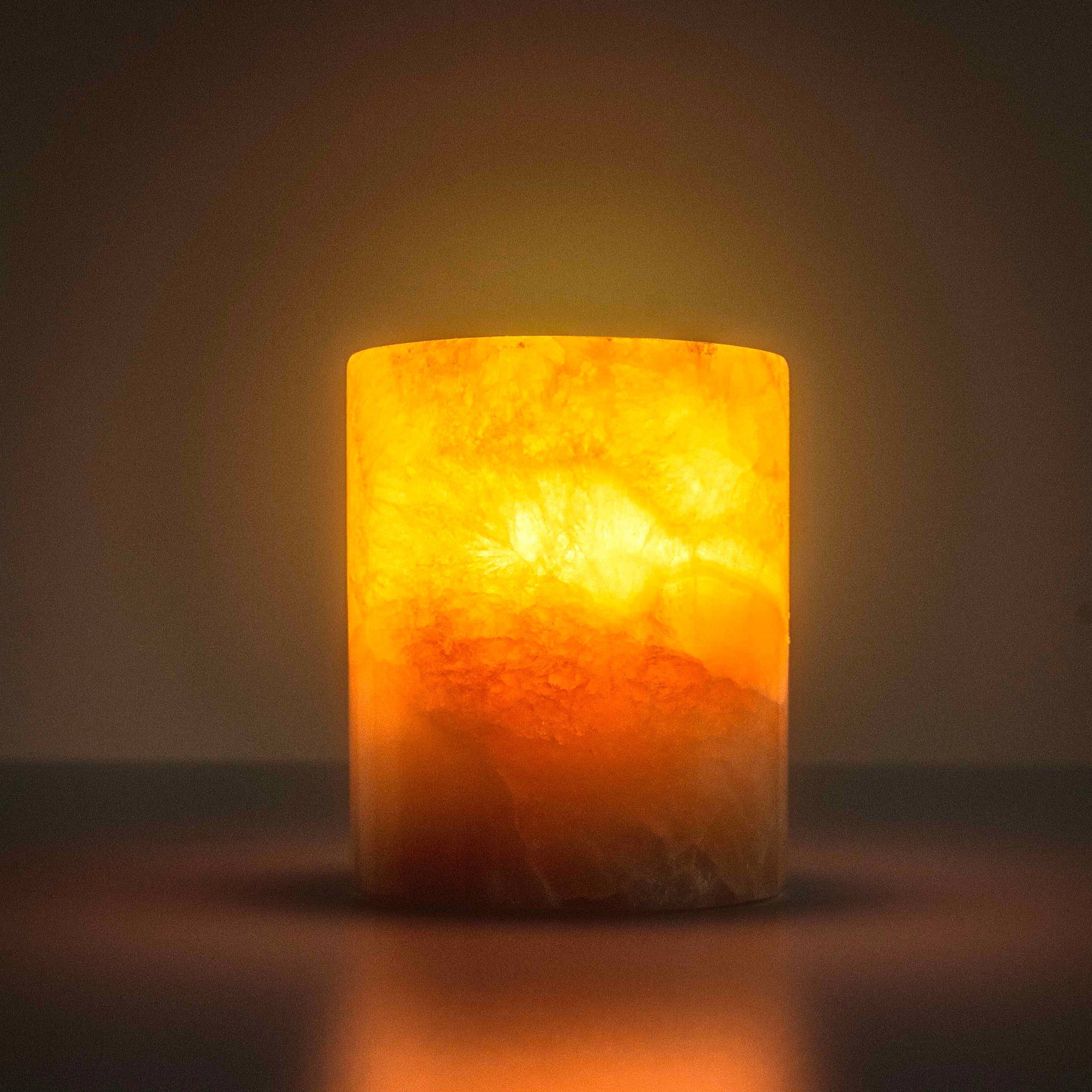 Cylindrical candle-like object with a warm glow on a dark background