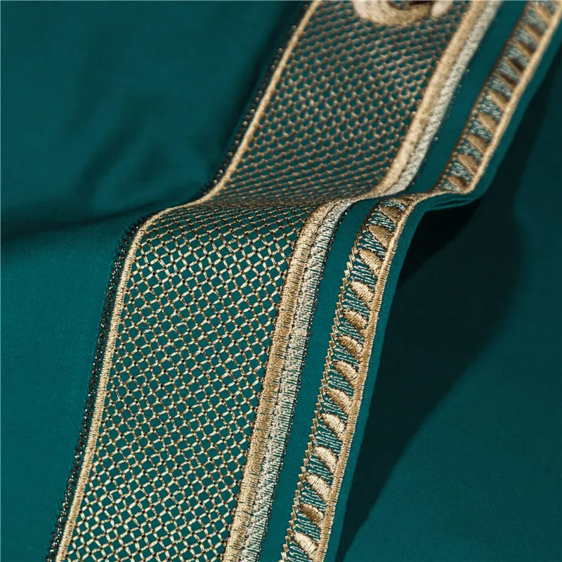 Close-up of a green fabric sheet with gold embroidery on a dark green background