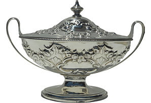 Silver trophy with intricate designs on a white background