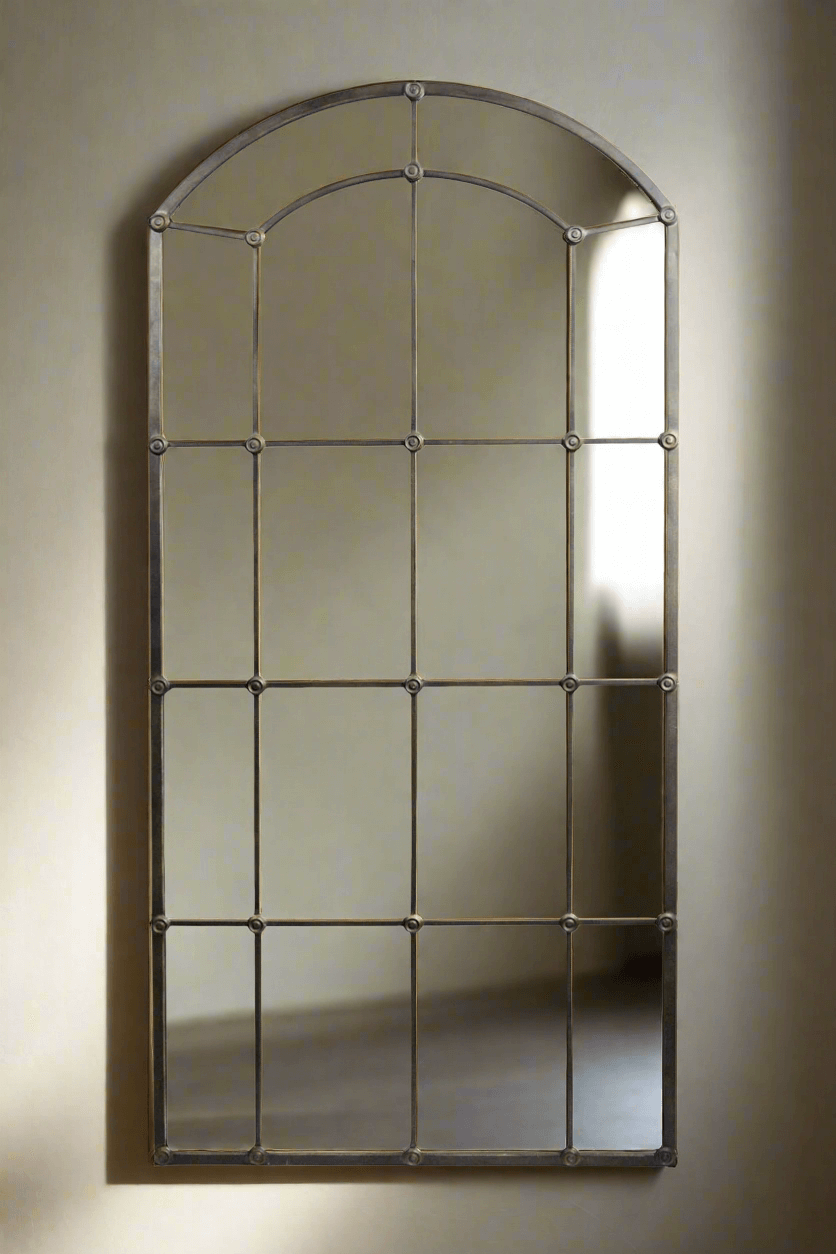 Arched mirror with metal frame on a wall