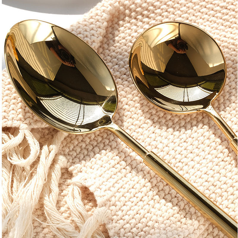 Two gold spoons on a textured beige surface