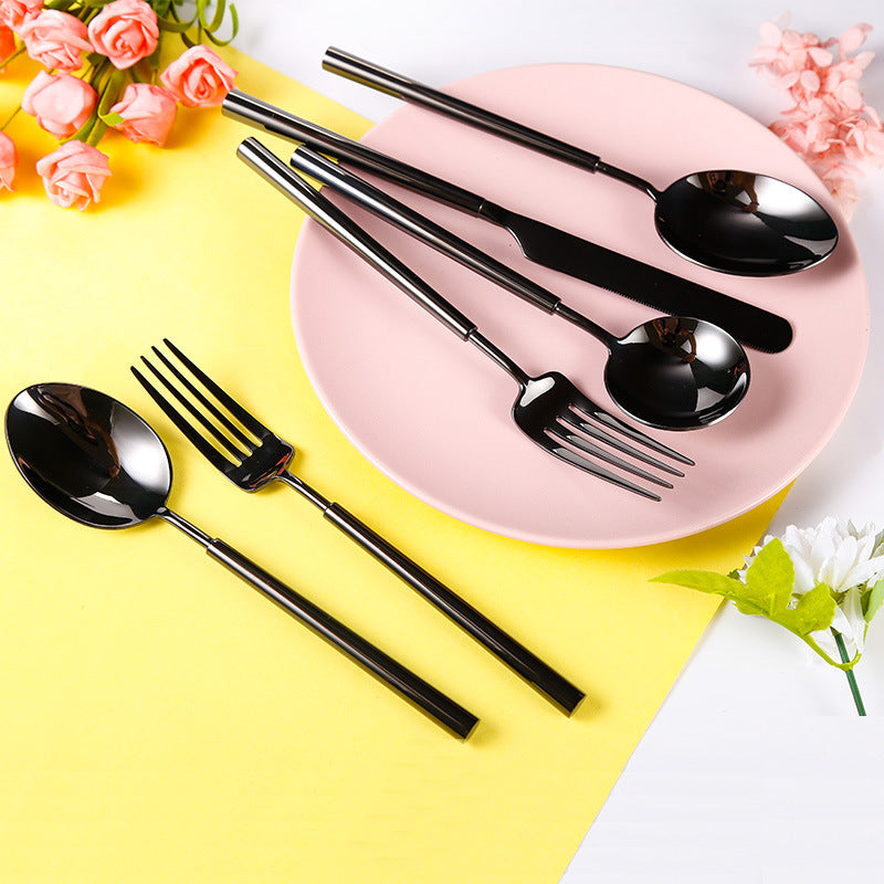 Black cutlery set on a pink plate with flowers around, on a yellow background
