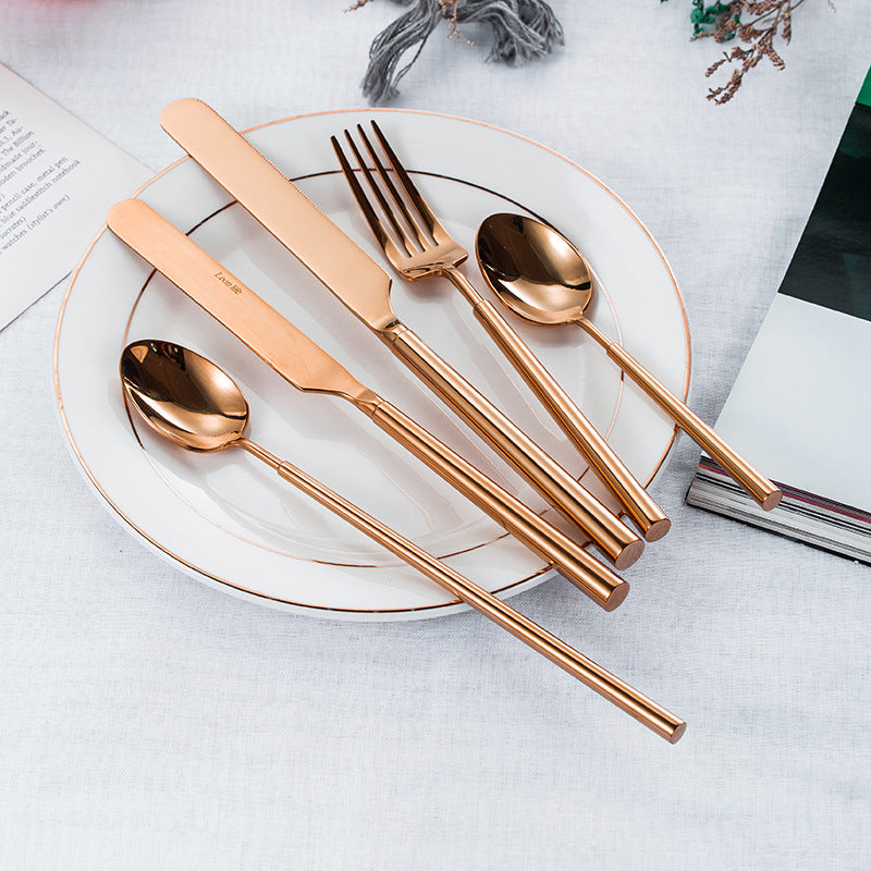 Rose gold cutlery set on a white plate with a white napkin.