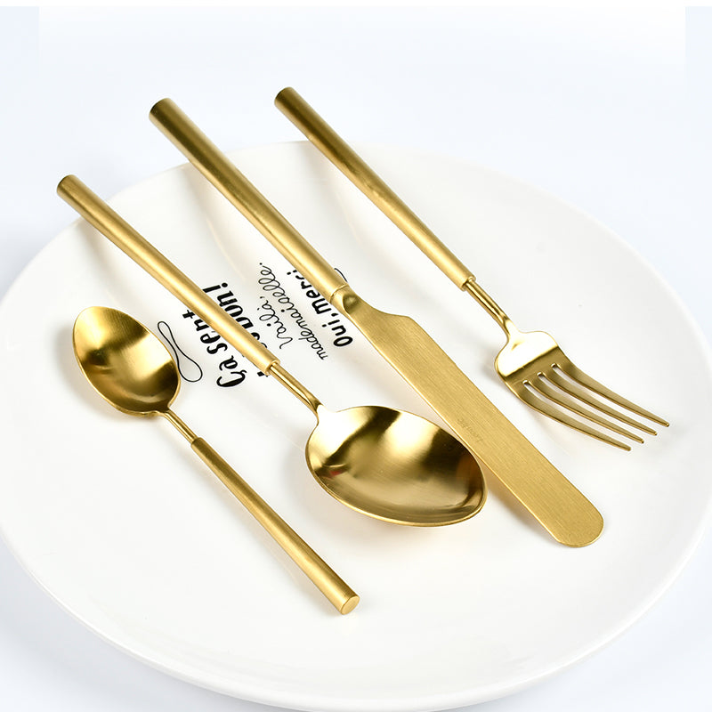 Set of gold cutlery including spoon, knife, and fork on a white plate with text.