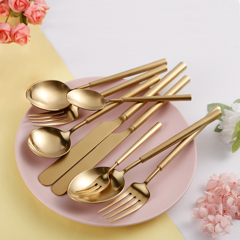 Gold cutlery set on a pink plate with flowers around