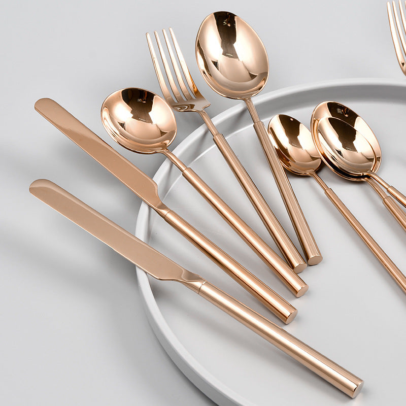 Rose gold flatware set on a white plate with a light gray background