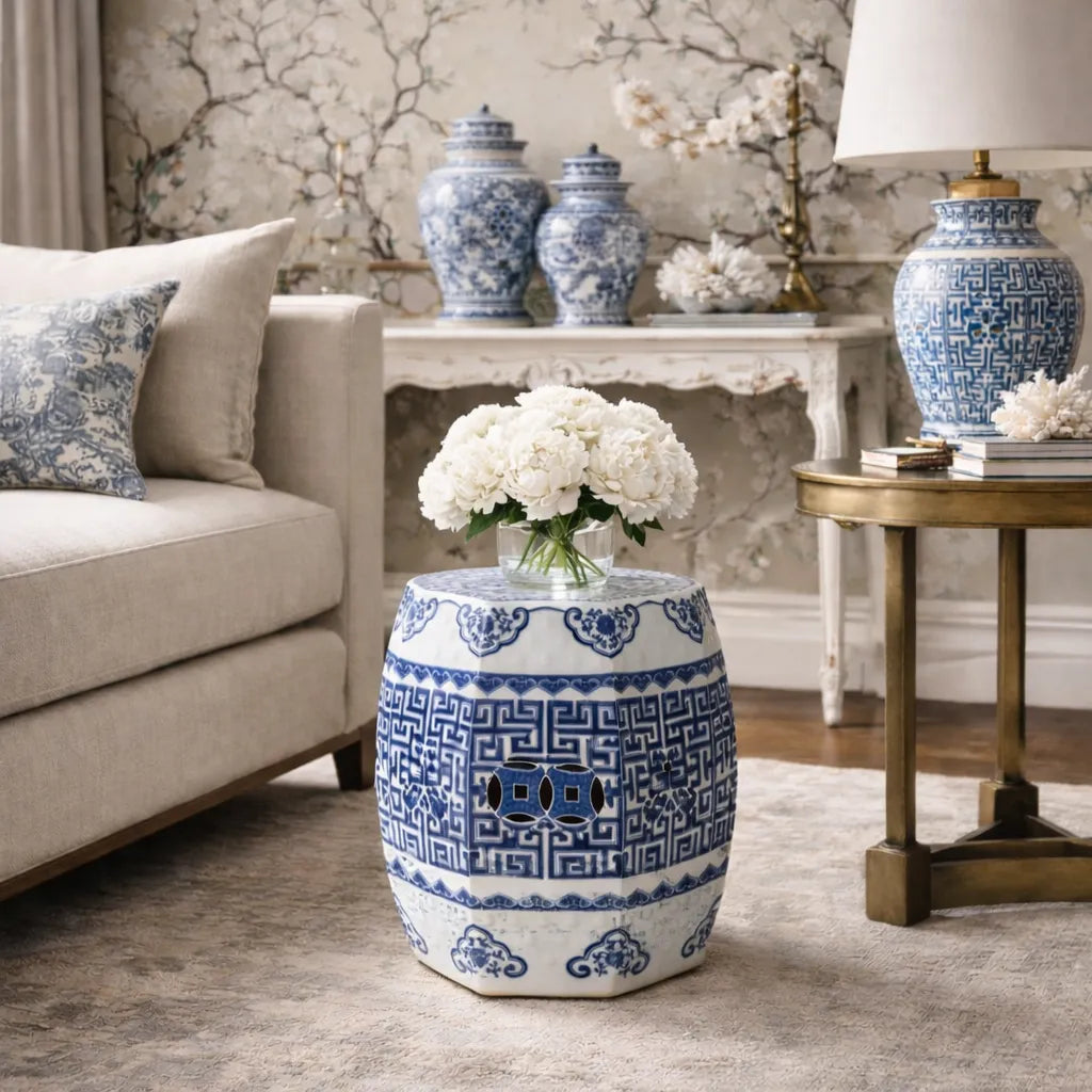 Decorative blue and white chinoiserie ceramic garden stool in a living room setting with floral arrangements.