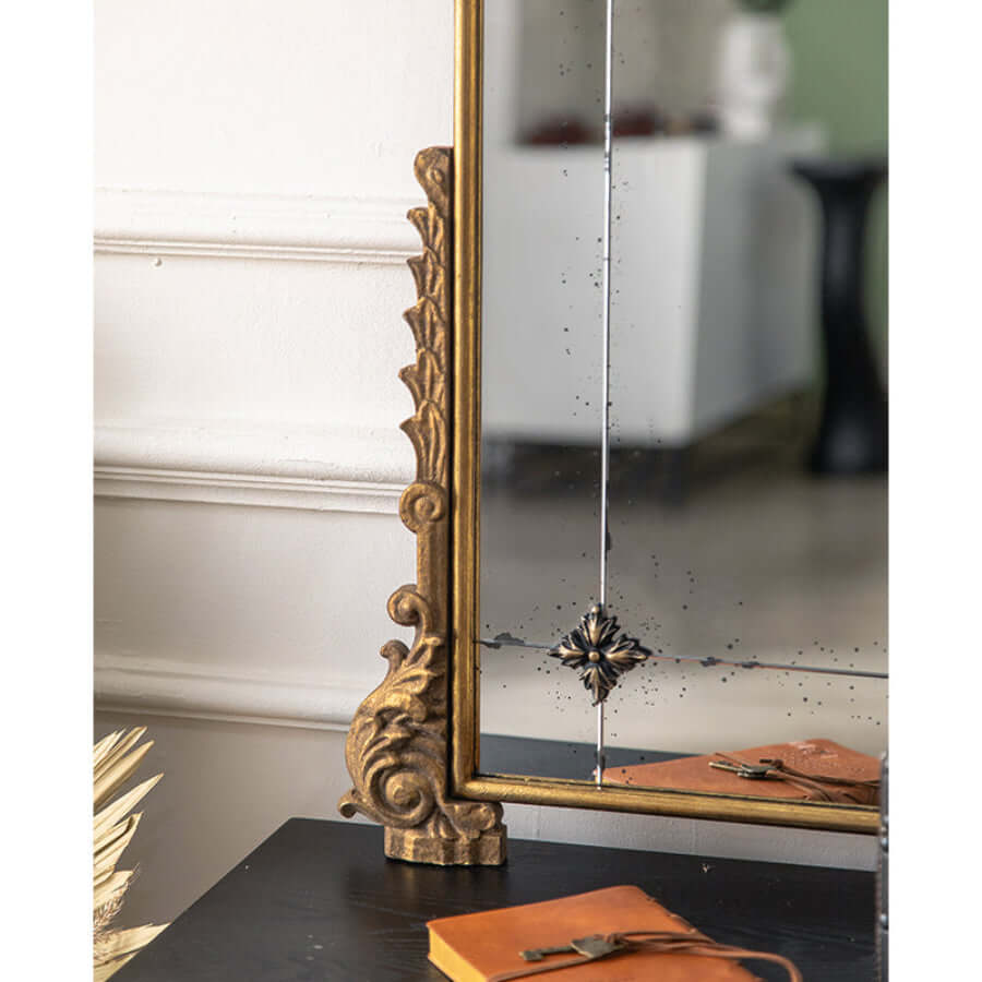 Decorative gold-framed mirror on a table with a blurred background