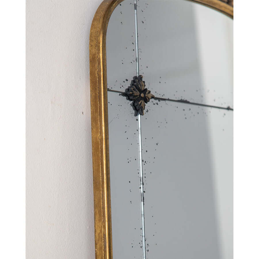 Gold-framed mirror with decorative element on a white wall
