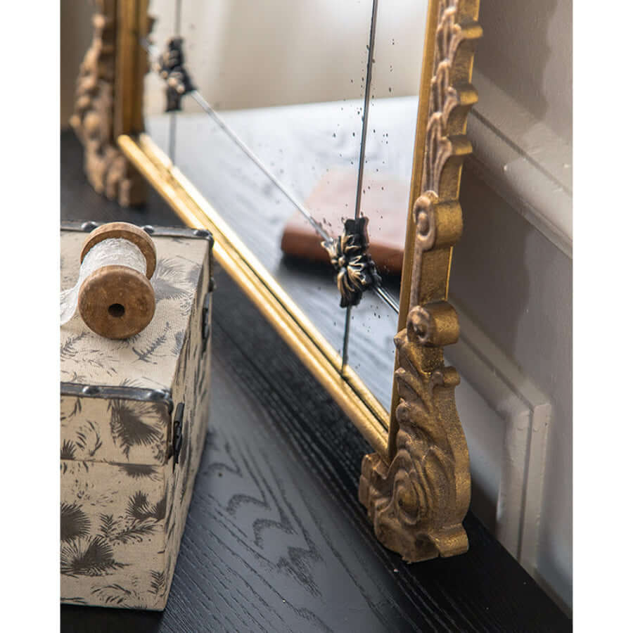 Decorative mirror with gold frame and decorative box on a surface