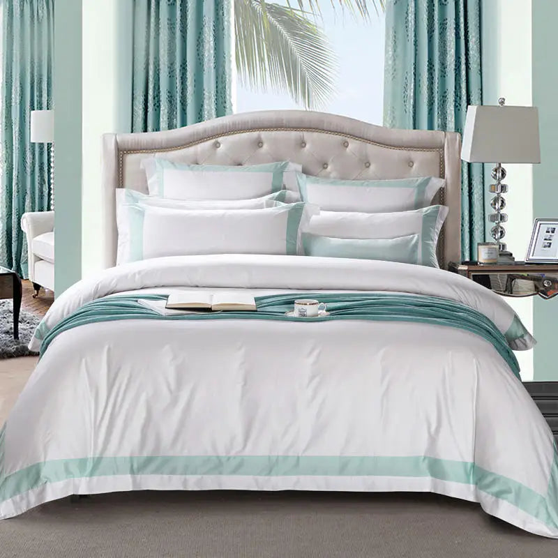 Neatly made bed with white and light blue bedding in a room with curtains and a lamp.
