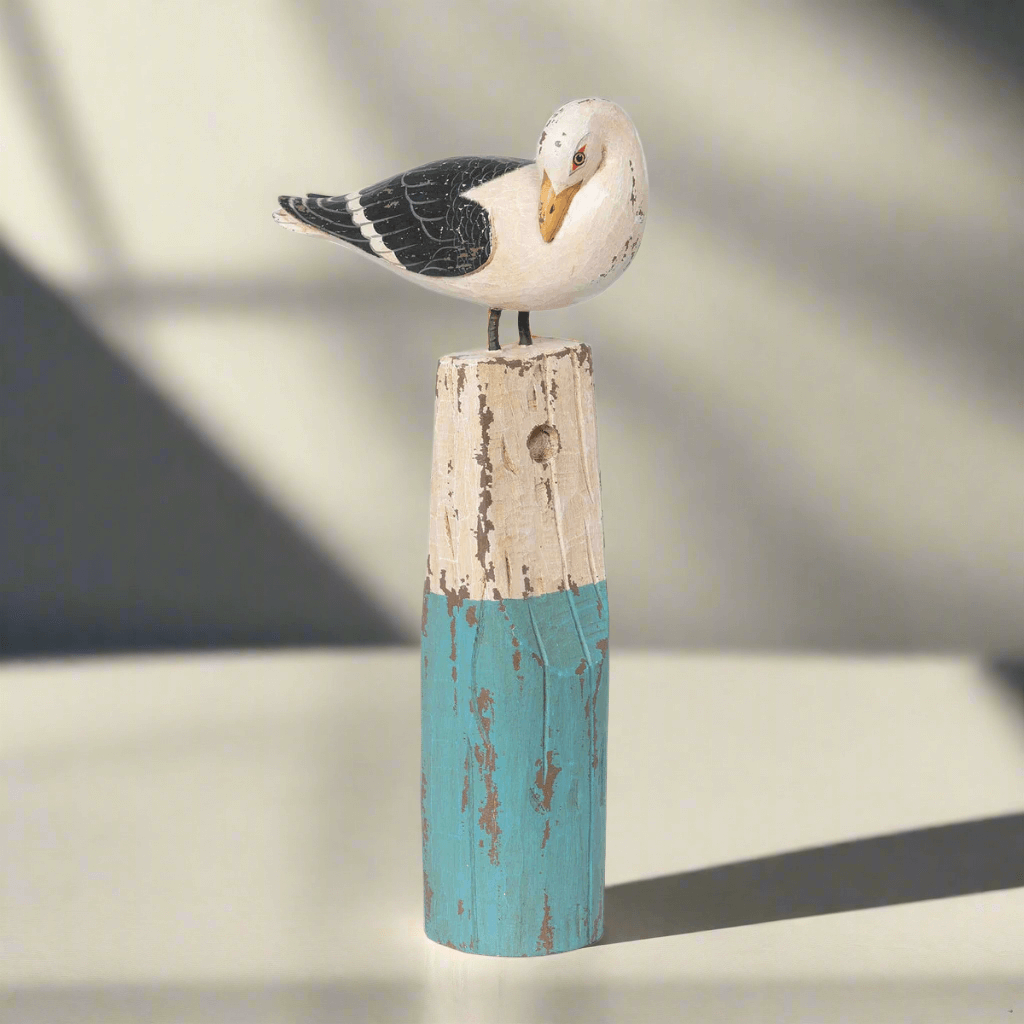 Decorative seagull perched on a wooden post with a blurred background