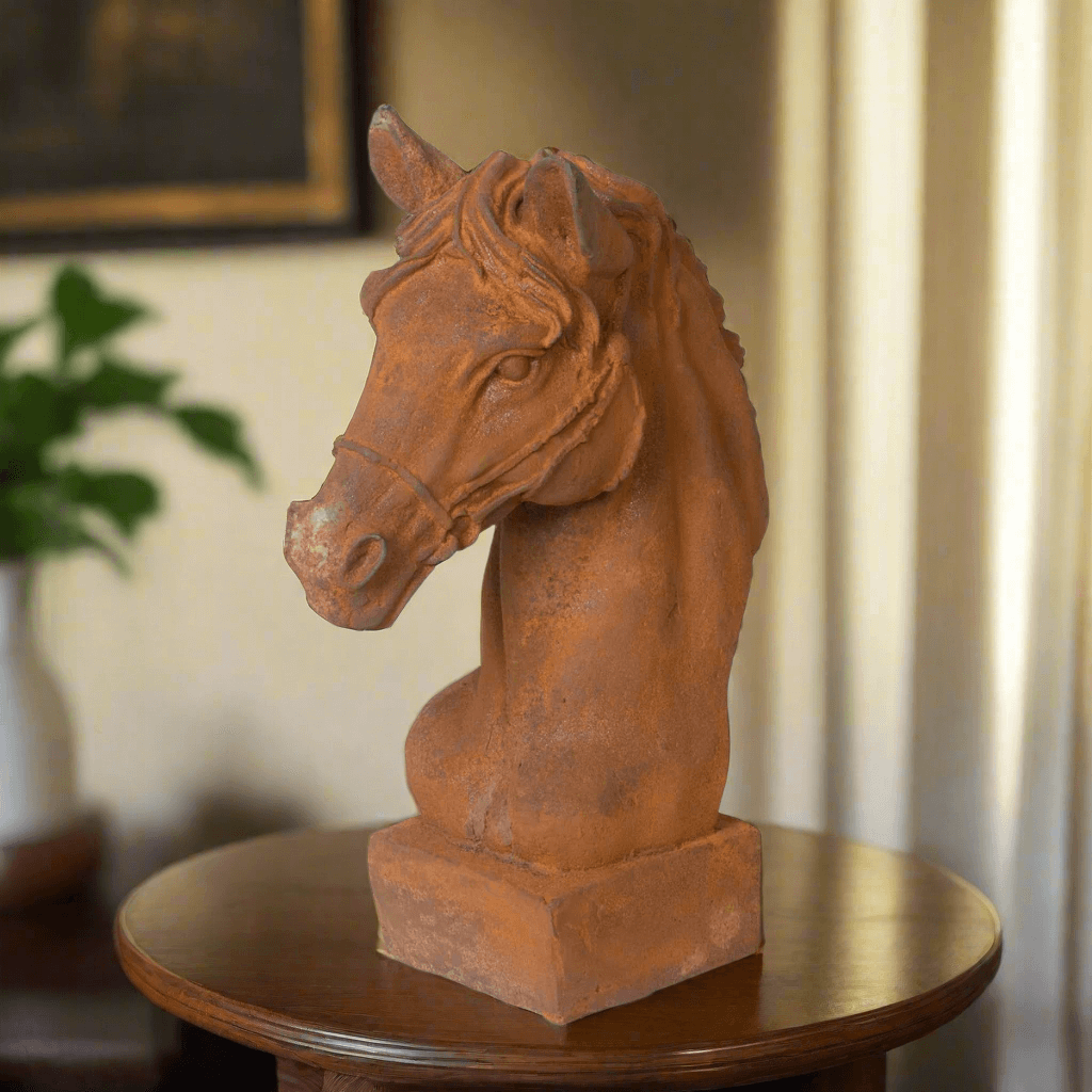 Terracotta horse head sculpture on a wooden table with a blurred background