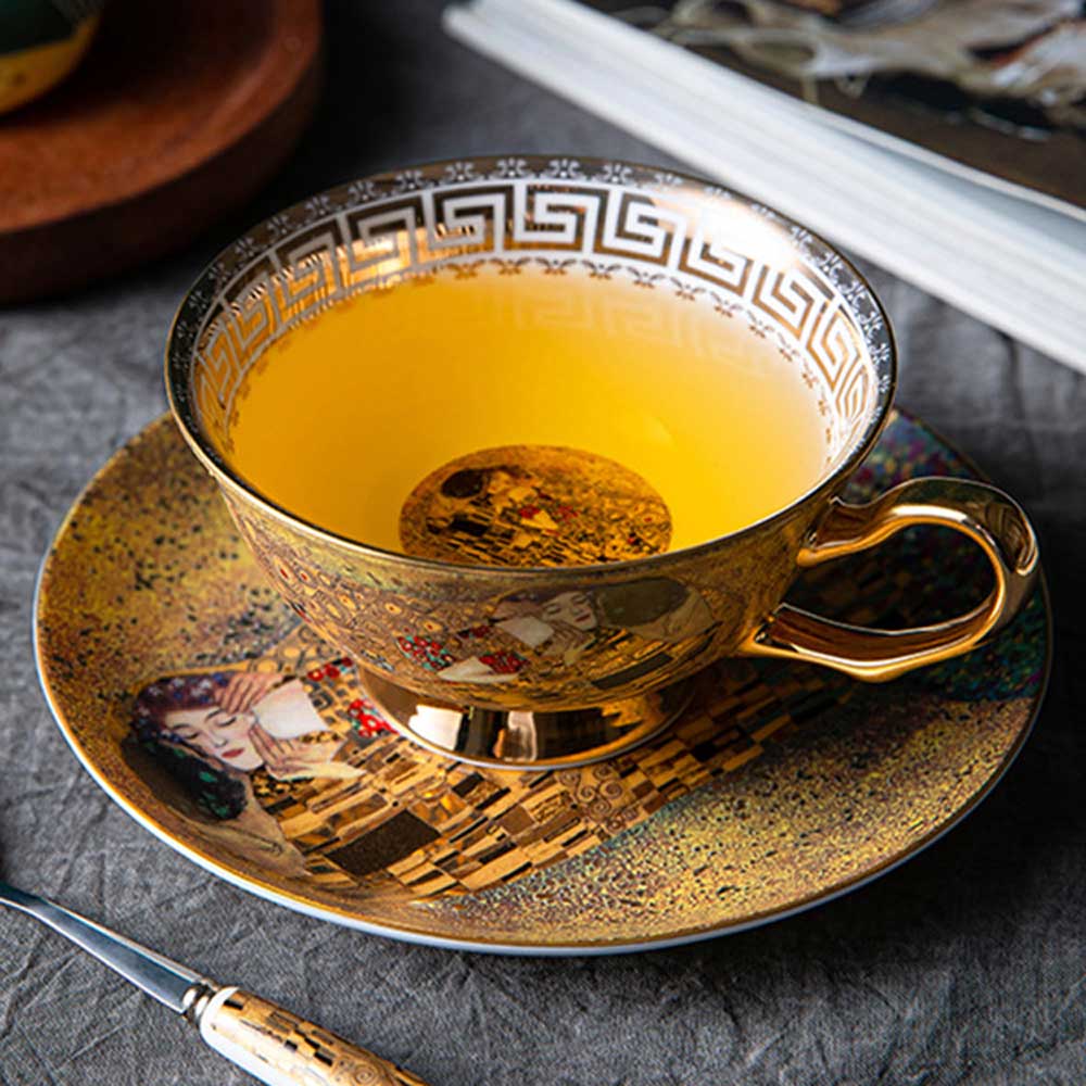 Decorative teacup with gold detailing on a matching saucer, filled with yellow liquid.