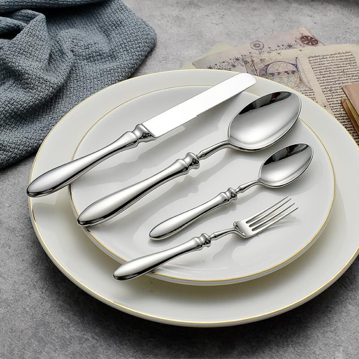 Silver cutlery set on a white plate with a gray background