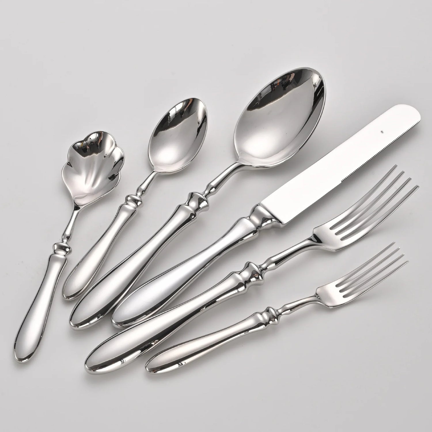 Set of silver cutlery including spoons and forks on a light gray background
