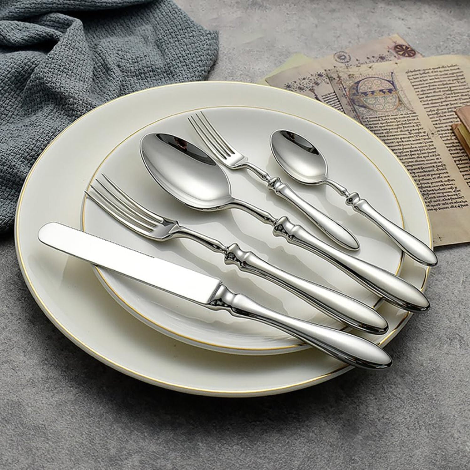 Silver cutlery set on a white plate with a gray background