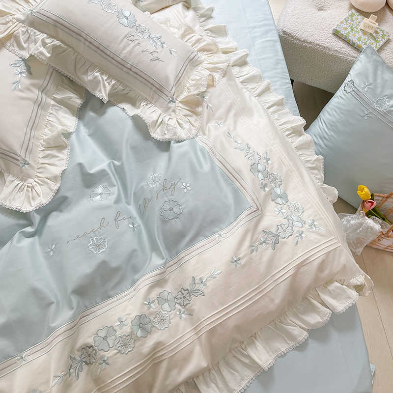 Embroidered bedding set with ruffled edges on a bed.