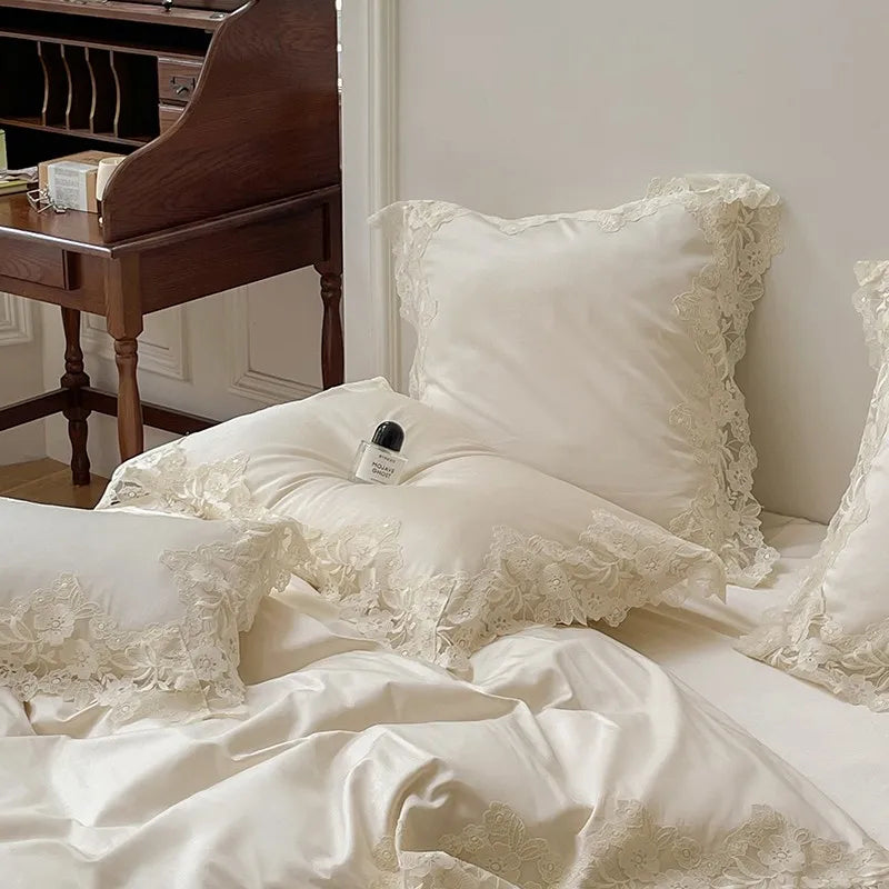 White lace bedding with pillows on a bed in a room with a wooden desk.