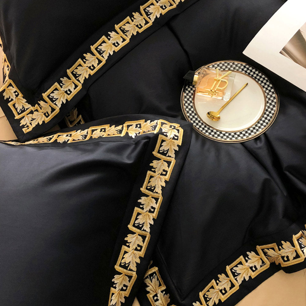 Black fabric with gold embroidery on a checkered plate with a cup and spoon.