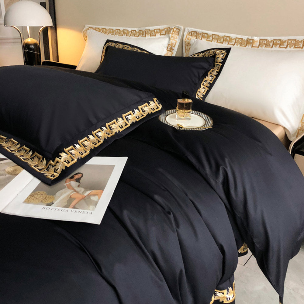 Black bedding set with gold trim on a bed in a bedroom.