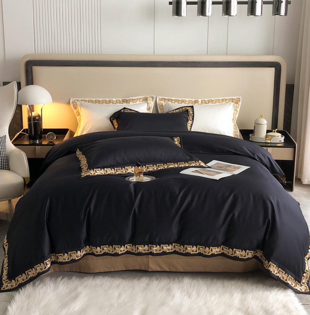 Black bedspread with gold trim on a bed in a modern bedroom.