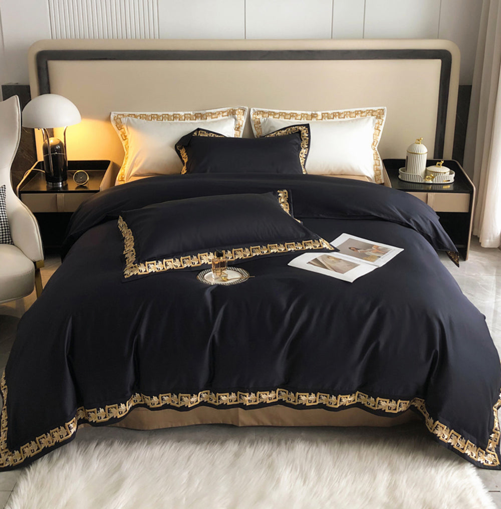 Black bedspread with gold trim on a bed in a bedroom setting.