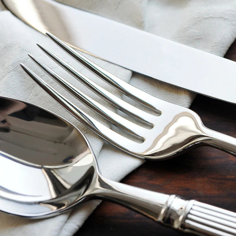 Silver fork and spoon on a wooden surface with a white napkin.