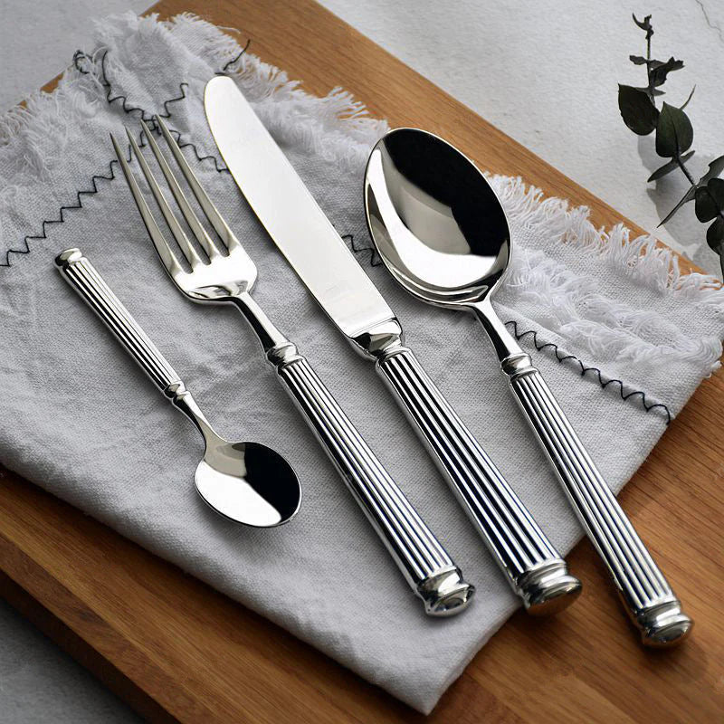 Silver cutlery set on a textured gray napkin with a wooden surface underneath.