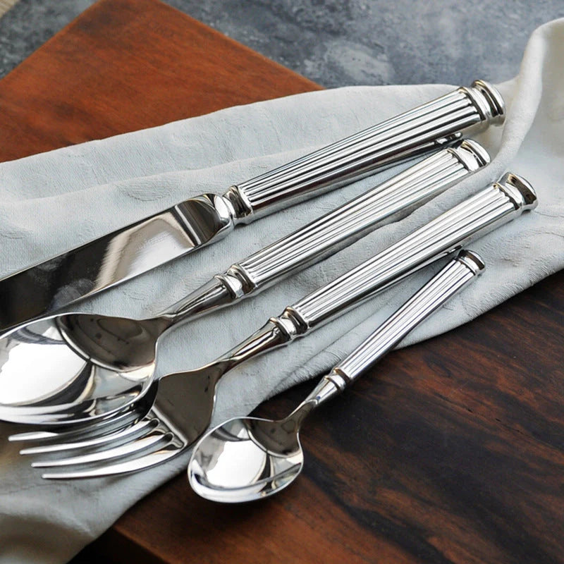 Set of silver cutlery on a wooden surface with a gray napkin