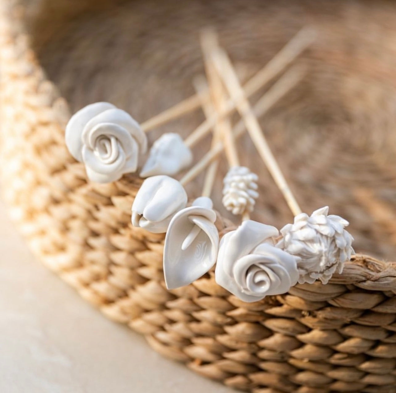 White floral diffuser sticks on a woven basket background