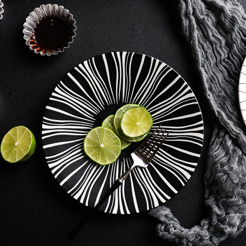 Black and white striped plate with lime slices on a dark surface