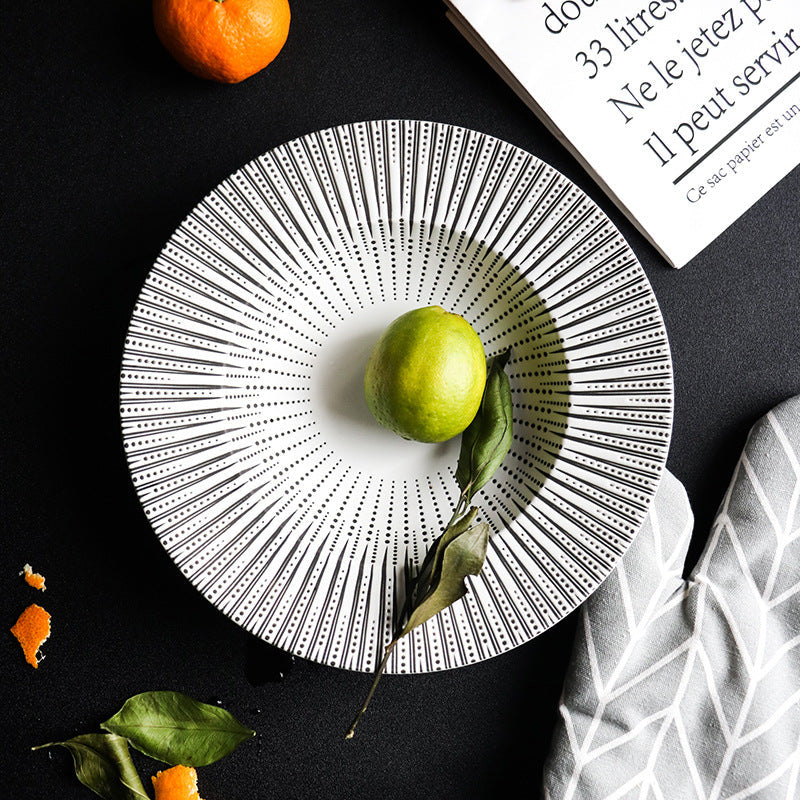 Decorative plate with a green apple on a black surface with an orange and book.