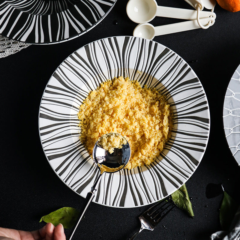 Black and white patterned plate with yellow food and a spoon on a dark surface