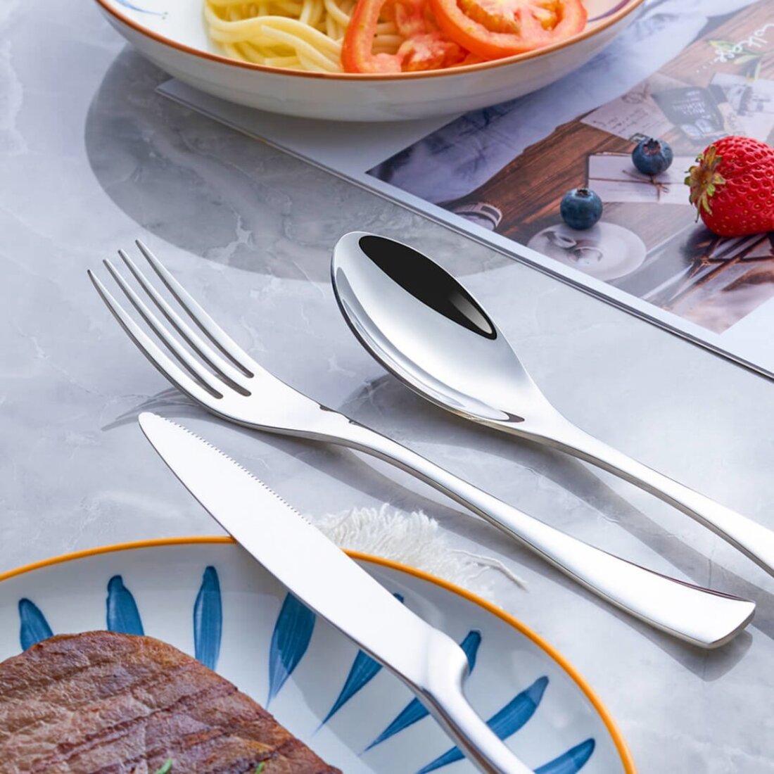 Stainless steel cutlery set on a table with food items
