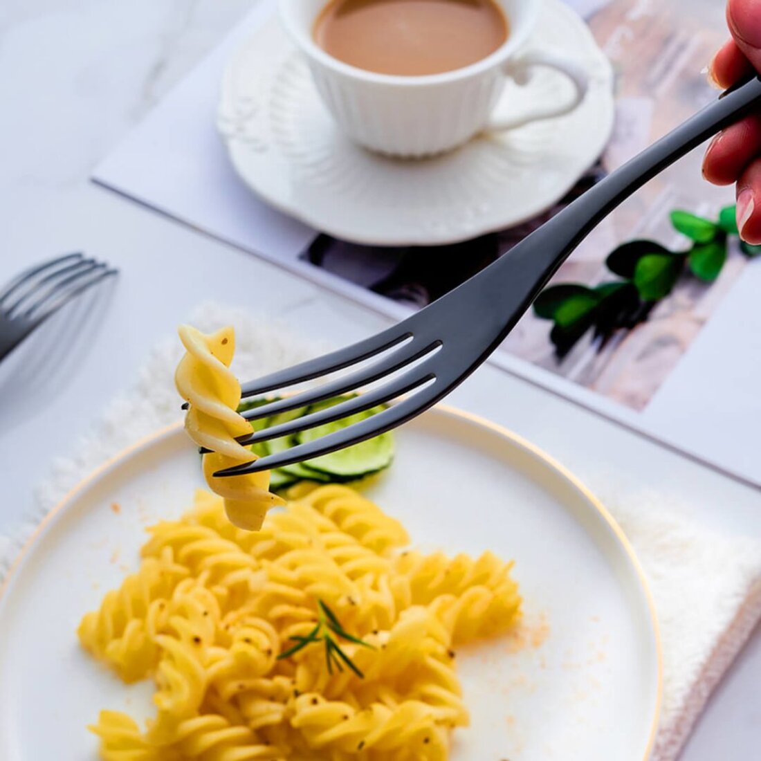 Fork twirling pasta with a cup of coffee in the background
