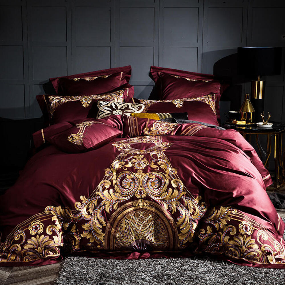 Luxurious burgundy and gold bedding set on a bed with decorative headboard.