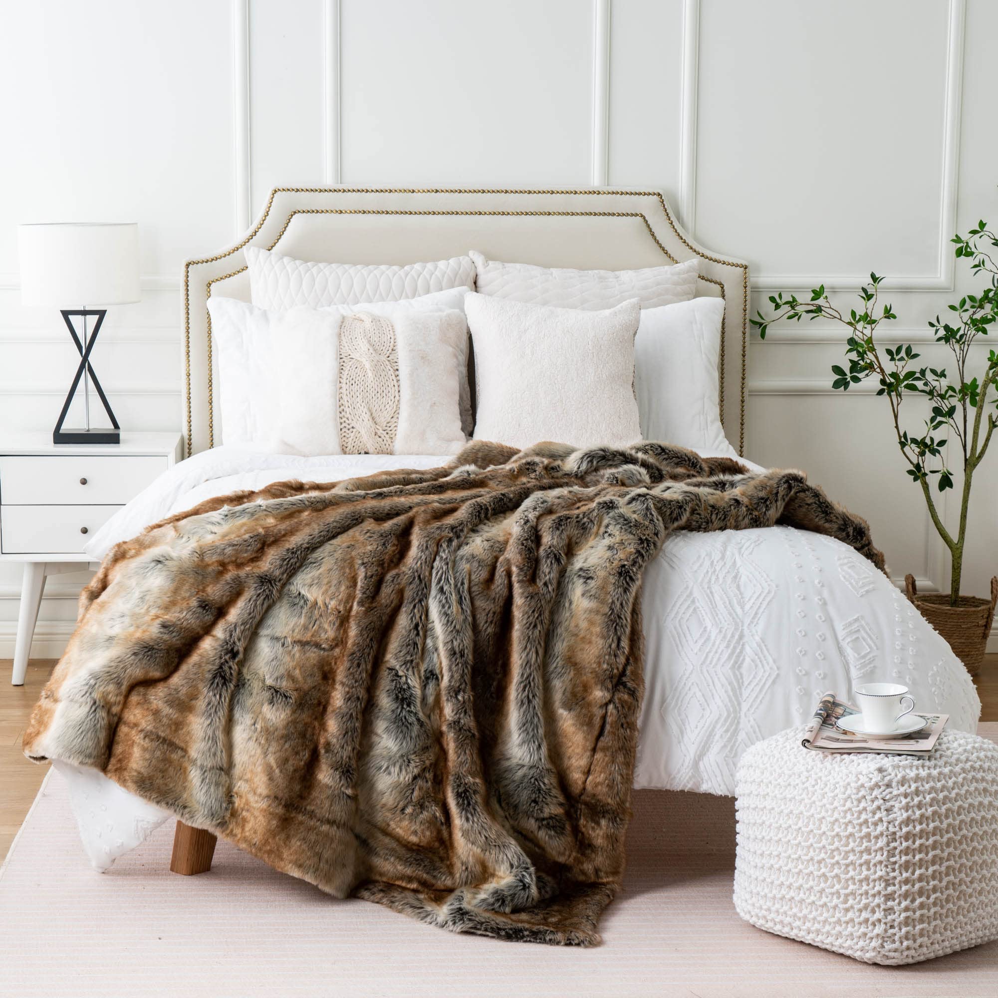 Bedroom with a bed featuring a fur throw blanket and white pillows.