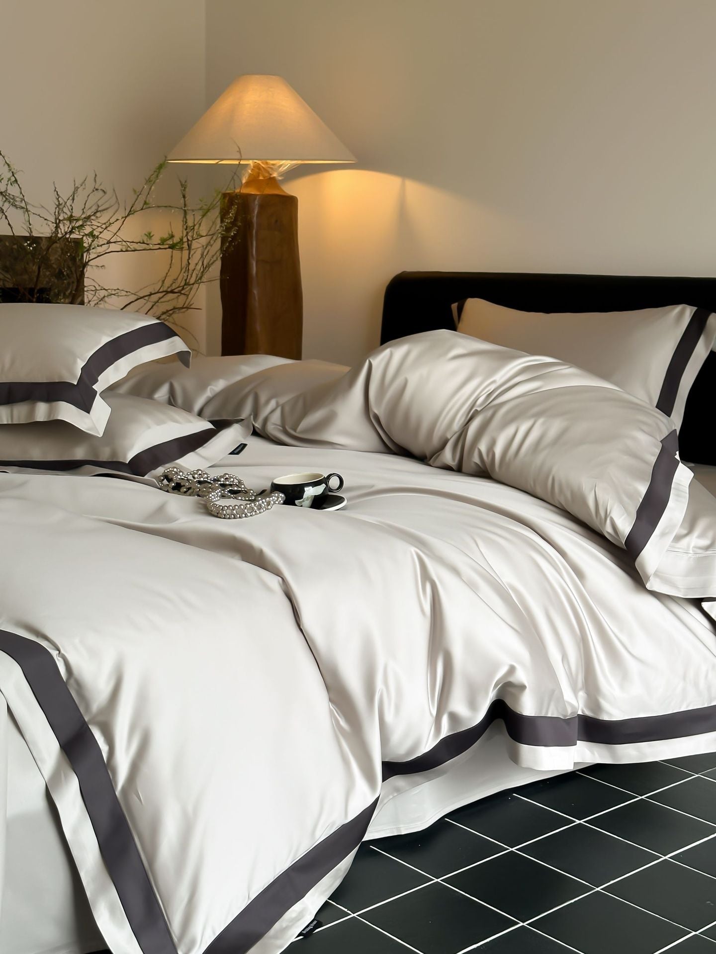 Neatly made bed with white bedding and gray trim in a bedroom setting.