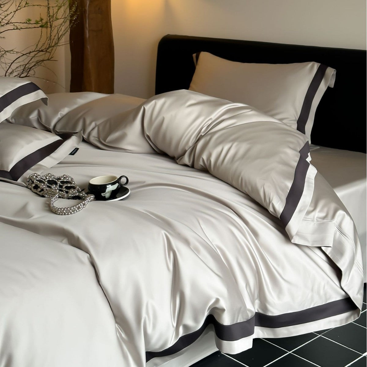 Neatly made bed with beige bedding and black trim in a bedroom setting.