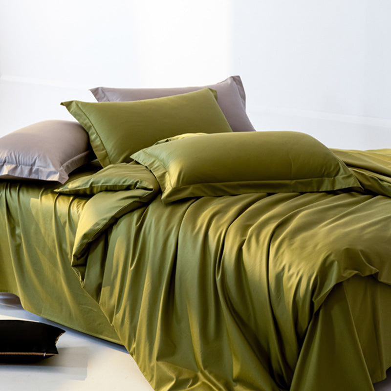 Green bedspread on a bed with pillows against a white background