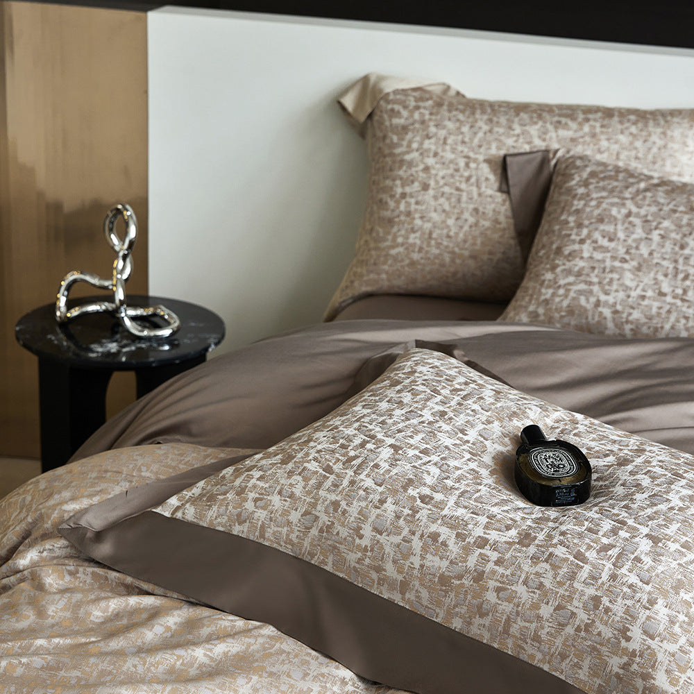 Bed with patterned bedding and pillows, nightstand with decorative object, and bottle on a pillow.