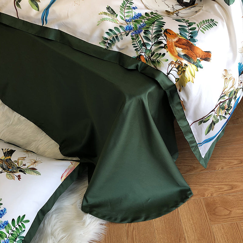 Green satin sheet with floral and bird design on a bed