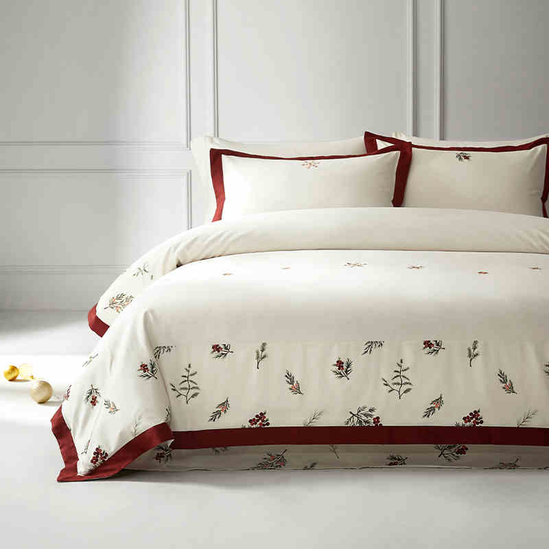 White bedding set with red accents and floral patterns on a bed in a bedroom.